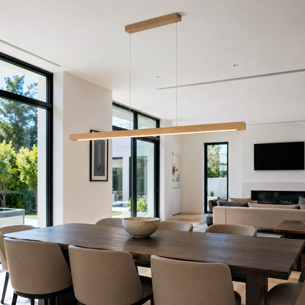 Alderline modern wood pendant light above a long dining table in an open-plan interior