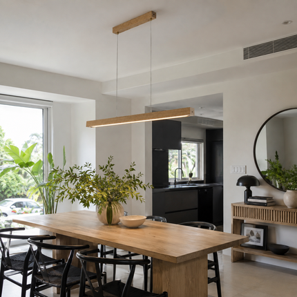 Light wood Alderline pendant illuminating a dining table beside a modern kitchen