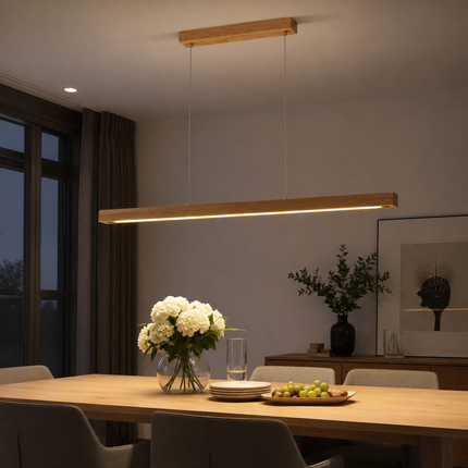 Illuminated Alderline linear LED pendant casting downward light over a dining table at night