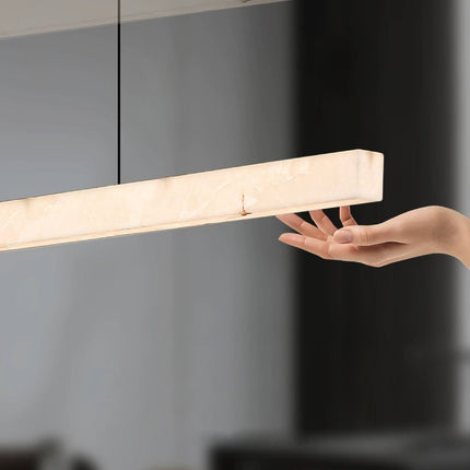Hand beside illuminated Nevella snowflake alabaster pendant light showing its slim profile