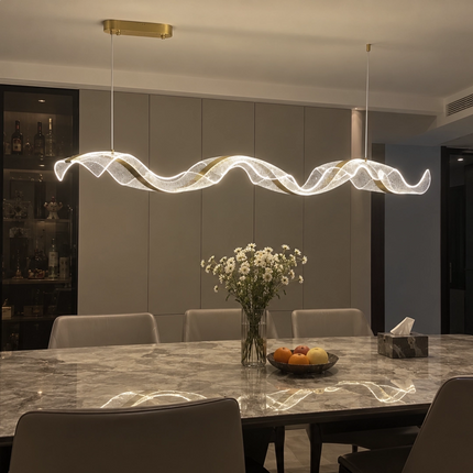 Gold-tone and clear acrylic Tidal Ribbon Chandelier above a dining table